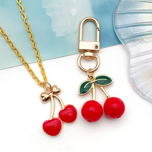 3D cherry fruit jewelry set featuring a gold necklace and keychain with red enamel charms