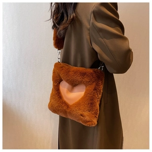Dettaglio della borsa a tracolla in peluche marrone con cuore rosa sulla modella
