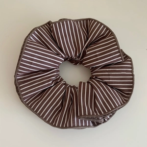 Detailed close-up of brown and white striped knit fabric scrunchie with pleated texture
