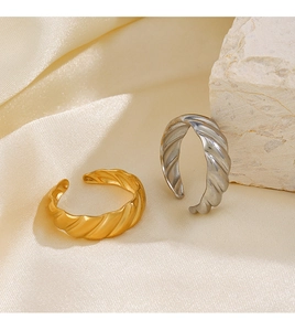 Close-up of gold and silver croissant rings on champagne silk with natural stone texture