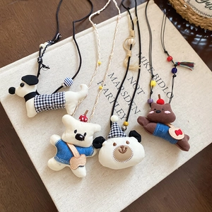 Detail of four handmade fabric cartoon animal necklaces on a vintage linen book background