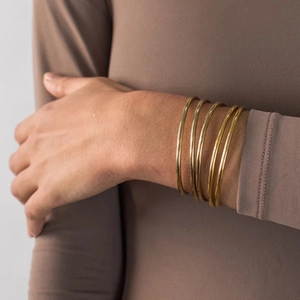 Macro detail of layered gold thin bangle bracelets on wrist for a minimalist jewelry style