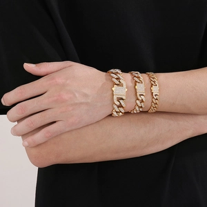 Close-up of three layered gold Cuban link bracelets with iced out diamond clasps