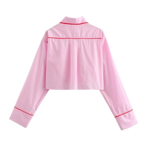 Dettaglio di camicia corta rosa a maniche lunghe con bordo rosso e colletto a risvolto