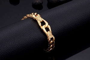 Detail of vintage men's gold stainless steel bracelet with engraved patterns on black leather