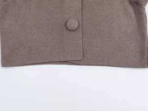 Close-up of knit fabric texture and matching fabric-covered button on brown cardigan