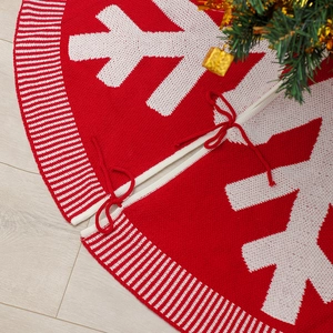 Gonna per albero di Natale in maglia rossa e bianca con fiocchi di neve su legno chiaro