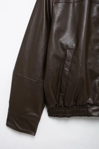 Detail of dark brown faux leather jacket showing pocket stitching and elastic hem texture