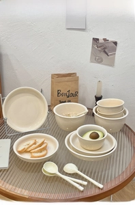 Minimalist cream white ceramic tableware set arranged on a glass table in a warm scene