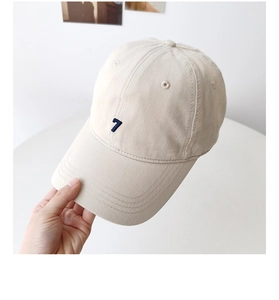 Close-up of beige cotton baseball cap featuring blue number 7 embroidery and soft texture