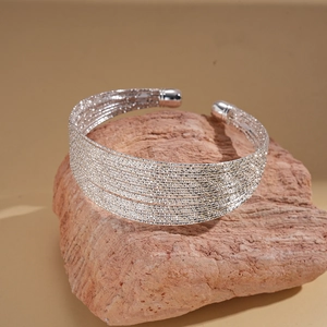 Macro detail of silver multilayer geometric open cuff bracelet with textured finish