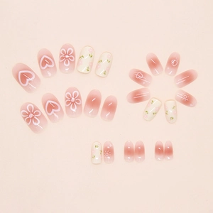 Macro detail of cream pink gradient press-on nails with floral and heart patterns