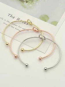 Detailed view of three metallic knot open bangles in gold, rose gold and silver finishes