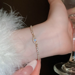 Detail of a sparkling evil eye bracelet with blue enamel and gold zirconia chain