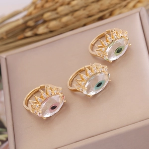 Three gold evil eye rings with cubic zirconia pavé on beige leather surface