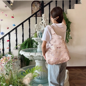 Detail of floral butterfly jacquard on light pink tote bag with stylish leather strap