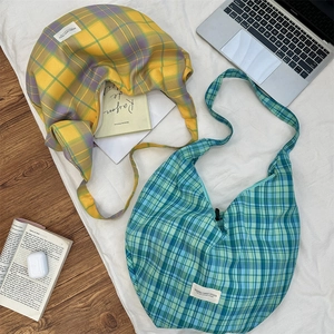 Detail of plaid canvas crossbody bag on white cloth with aesthetic lifestyle props