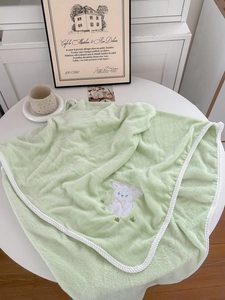 Detail of light green lamb towel featuring white sheep embroidery and braided edge