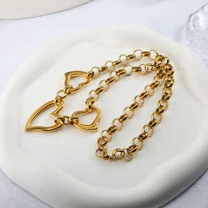Gold chunky link chain necklace with three heart pendants on a decorative tray