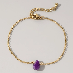 Detailed view of golden link bracelet featuring a faceted purple teardrop stone pendant