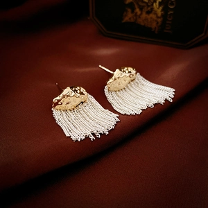 Close-up of dual-tone gold hammered metal and silver chain tassel drop earrings