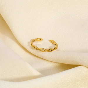 Macro shot of gold twisted line ring resting on ivory silk fabric with soft lighting