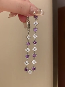 Detail of silver bracelet with purple cubic zirconia stones and white flower elements