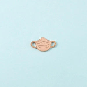 Détail d'un pendentif en métal en forme de masque or rose pour bijoux DIY sur bleu