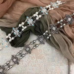 Y2K style silver and bronze pearl waist chains with gemstone charms on soft fabric