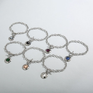 Détail de pendentifs ronds en cristal coloré et fermoir OT sur bracelets en titane