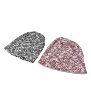Macro detail of soft knit texture and stitching on maroon and black mixed beanies