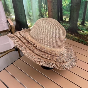 Detail of multi-layered tassel edges on a straw sun hat with woven texture