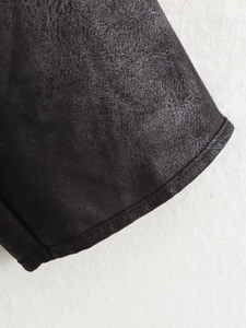 Gros plan du tissu en cuir noir mat et des bords de couture renforcés durables de la veste