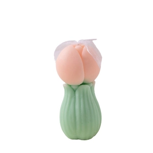 Vela aromática de tulipán rosa con base verde y lazo blanco sobre fondo blanco
