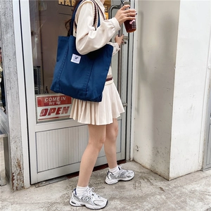 Navy blue canvas tote bag shown with model in minimalist cafe setting for daily commute