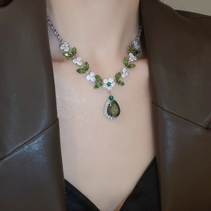 Primo piano di una collana d'argento con zirconi verdi a forma di pera e marquise