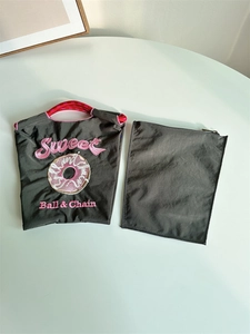 Detailed close-up of pink donut embroidery on a dark grey nylon tote bag texture