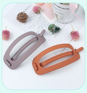 Detail view of purple and orange matte minimalist hair clips on a white surface