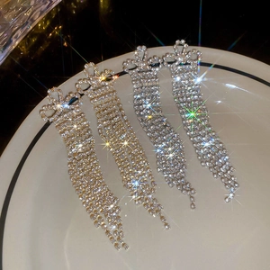 Close-up of gold and silver bowknot tassel earrings with rhinestones in a tray