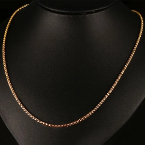 Détail d'un collier chaîne box en acier titane doré sur un buste de mannequin noir