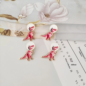 Detail shot of four cute astronaut dinosaur enamel brooches on floral fabric background