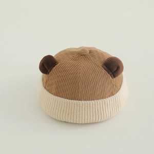 Detail of knitted baby hat featuring corduroy bear ears and thick ribbed texture