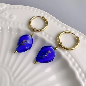 Detail of 18K gold hoop earrings with blue glass drop pendants and purple rose inlay