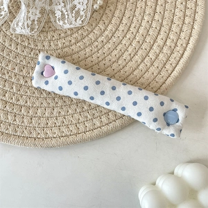 Close-up of fabric cable organizer with blue polka dots and heart button on woven mat