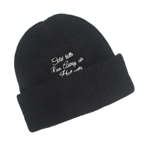 Detailed view of black ribbed knit beanie featuring white Cold Latte letter embroidery