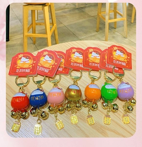 Flat lay of seven colorful Maneki Neko lucky cat charms with gold bells on wooden background