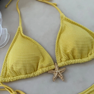 Detail of yellow waffle texture bikini top with a golden starfish metal charm
