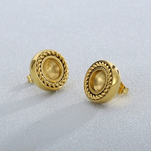 Golden round stud earrings with intricate twisted rope edge detail on a grey surface
