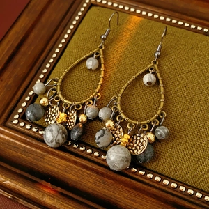 Close-up of vintage bamboo-style bronze drop earrings with marble beads and tassels