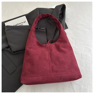 Detail showing Burgundy suede tote bag texture with minimalist design on textured fabric